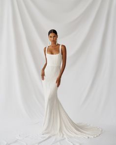 a woman in a white wedding dress posing for the camera with her hands on her hips