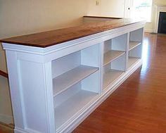 an empty room with wooden flooring and white shelves on either side of the counter