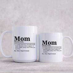 two white coffee mugs with the words mom and definition printed on them, sitting next to each other