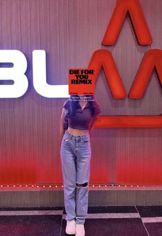 a woman standing in front of a red and white wall with the words blue on it