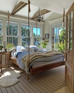 a bedroom with a canopy bed and lots of pillows on the floor, windows to the outside