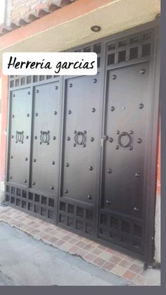 an iron gate with the words hereria garcias on it in front of a brick building