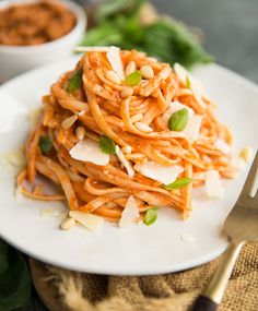 a white plate topped with pasta and garnished with parmesan cheese