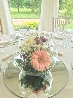 there is a vase with flowers in it on top of a glass platter at the table