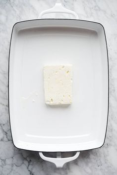 a square piece of cheese sitting on top of a white plate