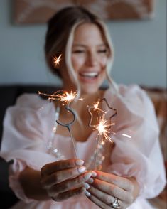 a woman holding two sparklers in her hands