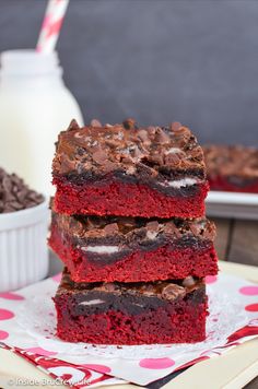 three red velvet brownies stacked on top of each other next to a glass of milk