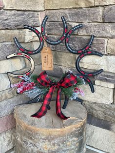 a deer head with antlers and plaid bow on top of a tree stump in front of a stone wall