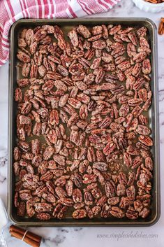 a baking pan filled with pecans on top of a marble counter