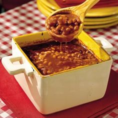 a spoon full of baked beans being lifted from a casserole dish