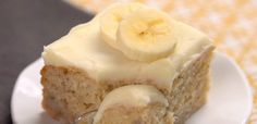 a piece of banana cake with white frosting and bananas on top is being held by a fork