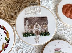 four embroidery hoops with houses and trees on them