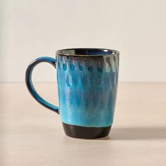 a blue and black coffee cup sitting on top of a table