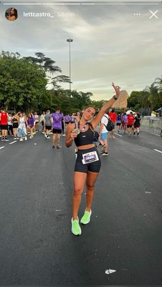 a woman is running down the street with her arms in the air and other people behind her