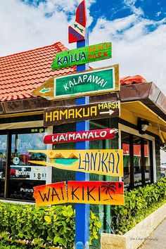 a sign post with many different signs on it in front of a building that says kaluua water