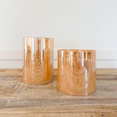 two clear glass candlesticks sitting on top of a wooden table next to each other