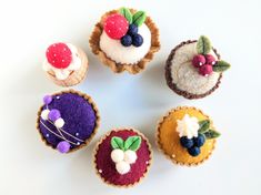 there are six small cupcakes made out of felt and decorated with fruit on top