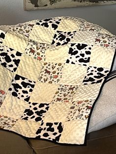 a black and white cow print quilt on the back of a couch with a pillow