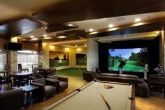 a man playing a game of pool in a large room with couches and tables