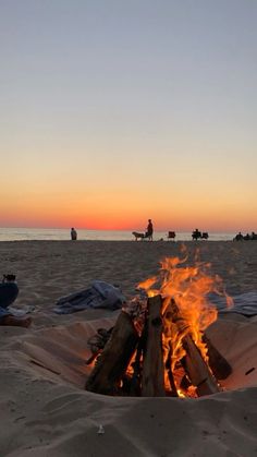 a fire pit on the beach with people in the background