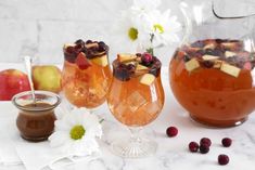 two glasses filled with liquid and fruit next to some other items on a table top