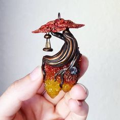 a hand holding a miniature figurine with an umbrella on it