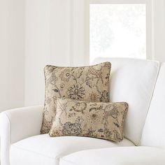 two pillows sitting on top of a white couch