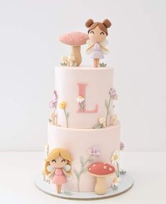 a three tiered cake with two figurines on top and flowers around it