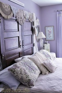 a bedroom with purple walls and white bedding, two large wooden doors on either side of the bed