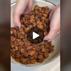 two hands are scooping nuts into a bowl with another person's hand in the background