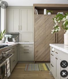 a kitchen with white cabinets and wood flooring is pictured in this image, there are flowers on the counter