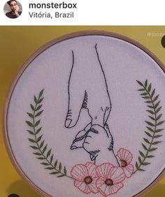 a close up of a embroidery on a table with a person holding the hand of another person