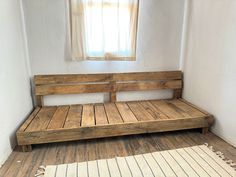 a wooden bench sitting on top of a hard wood floor next to a white rug