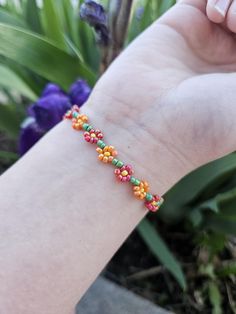 a person is holding onto a bracelet with beads on it and flowers in the background