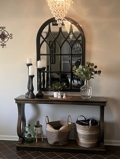 a table with baskets and candles on it in front of a mirror, chandelier