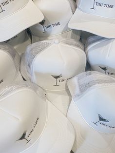 white hats with the words time and martinis printed on them are piled up together