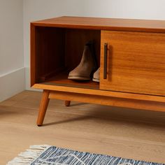 a pair of shoes sitting on top of a wooden cabinet next to a blue rug