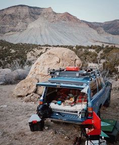 an suv parked on the side of a mountain with its roof open and luggage in the back