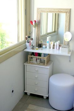 a small white vanity in a bathroom next to a window