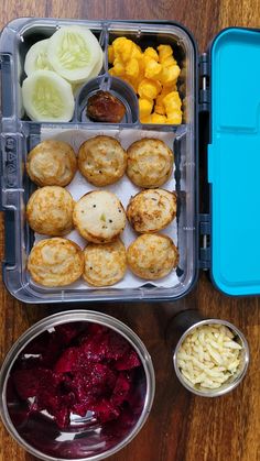 a plastic container filled with food on top of a wooden table next to two bowls