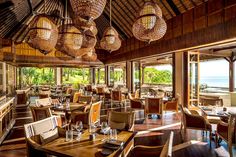 a restaurant with wooden tables and chairs overlooking the ocean