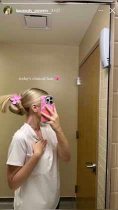 a woman taking a selfie in front of a mirror with her hair pulled into a pony tail