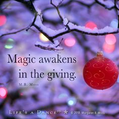 a christmas ornament hanging from a tree with lights in the background and a quote about magic awakes in the giving