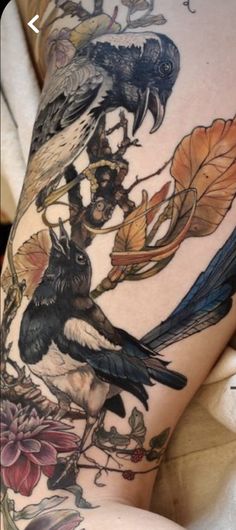 a woman's thigh with tattoos on her legs and two birds sitting on top of each other