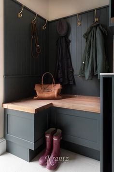 a pair of rain boots sitting on top of a bench next to a coat rack