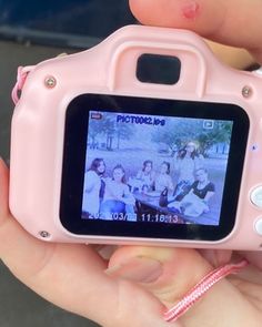 a person holding up a pink camera in their hand with pictures on the front and back