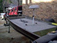 there is a boat that is parked next to a brick building with a red truck in the background