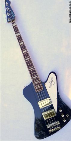 a black and white electric guitar laying on top of a white surface with its neck missing