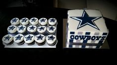 a table topped with cupcakes covered in frosting next to a box of cookies