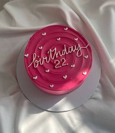 a pink birthday cake with hearts on it